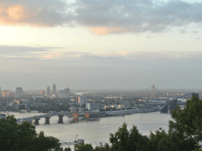 Paisagem ao horizonte de uma grande cidade rodeado de um rio com pontes e vegetações