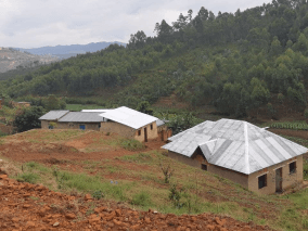 Comunidade de casas em tijolos sem acabamentos no topo de um morro com vegetações ao horizonte.
